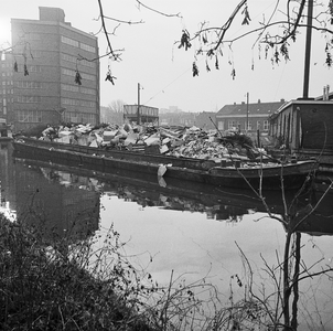 850491 Afbeelding van een met huisvuil volgestorte vuilnisschuit in de Biltsche Grift op het Vaaltterrein te Utrecht.